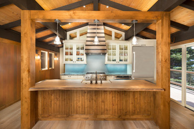 Eat-in kitchen - mid-sized rustic galley light wood floor eat-in kitchen idea in Sacramento with blue backsplash, an island, a farmhouse sink, glass-front cabinets, white cabinets, glass tile backsplash, stainless steel appliances and granite countertops