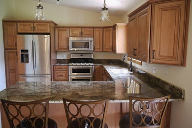 Mid-sized elegant u-shaped eat-in kitchen photo in Grand Rapids with an undermount sink, raised-panel cabinets, medium tone wood cabinets, granite countertops, stainless steel appliances and a peninsula