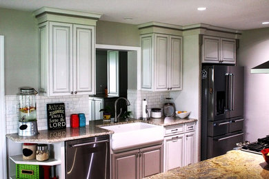 Küche mit Landhausspüle, profilierten Schrankfronten, weißen Schränken, Granit-Arbeitsplatte, Küchenrückwand in Weiß und Küchengeräten aus Edelstahl in Orlando