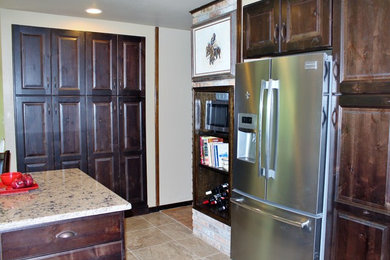 Mid-sized elegant l-shaped ceramic tile enclosed kitchen photo in New Orleans with a double-bowl sink, raised-panel cabinets, dark wood cabinets, granite countertops, stainless steel appliances and an island