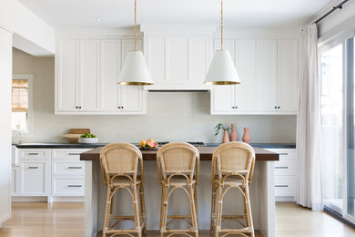 Example of a mid-sized cottage light wood floor and beige floor kitchen design in San Francisco with shaker cabinets, white cabinets, soapstone countertops, an island, black countertops and beige backsplash