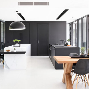 Design ideas for a contemporary galley eat-in kitchen in Sunshine Coast with an undermount sink, flat-panel cabinets, black cabinets, black splashback, multiple islands, white floor and white benchtop.