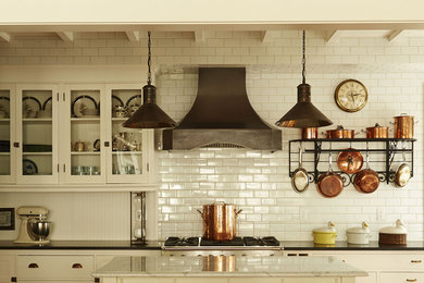 Inspiration for a timeless kitchen remodel in Milwaukee with glass-front cabinets, white cabinets, white backsplash, subway tile backsplash and an island