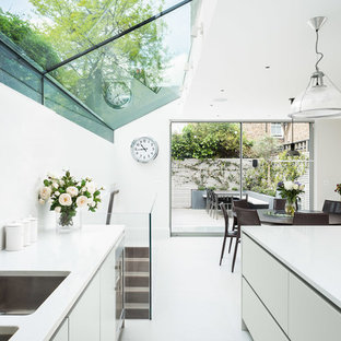 Design ideas for a medium sized contemporary galley kitchen/diner in Other with a double-bowl sink, flat-panel cabinets, an island, white floors, white cabinets and stainless steel appliances.