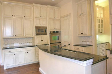 Ejemplo de cocina clásica de tamaño medio con armarios con paneles con relieve, puertas de armario blancas y dos o más islas