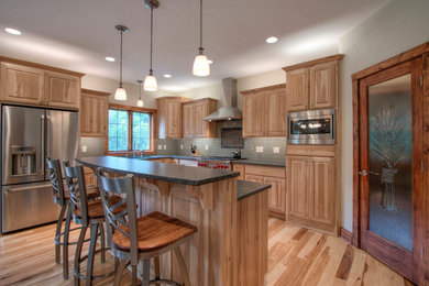 Inspiration for a rustic medium tone wood floor kitchen pantry remodel in Milwaukee with a single-bowl sink, raised-panel cabinets, medium tone wood cabinets, granite countertops, glass tile backsplash, white appliances and a peninsula