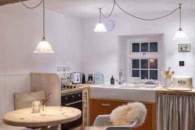 Medium sized u-shaped kitchen/diner in Devon with a belfast sink, wood worktops, ceramic splashback, stainless steel appliances, light hardwood flooring, no island and exposed beams.