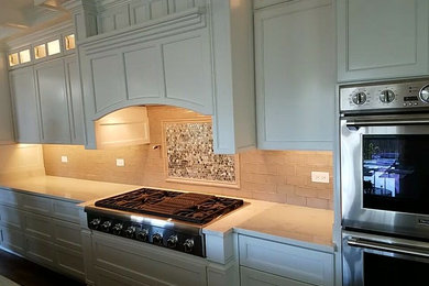 Modelo de cocina clásica de tamaño medio con puertas de armario blancas, salpicadero multicolor, salpicadero con mosaicos de azulejos y electrodomésticos de acero inoxidable