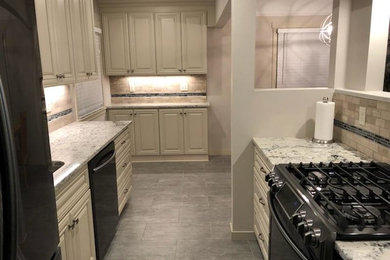 Inspiration for a mid-sized timeless galley vinyl floor and gray floor eat-in kitchen remodel in Minneapolis with an undermount sink, raised-panel cabinets, white cabinets, granite countertops, multicolored backsplash, ceramic backsplash, black appliances and gray countertops