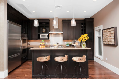 デンバーにあるトランジショナルスタイルのおしゃれなキッチン (シェーカースタイル扉のキャビネット、黒いキャビネット、シルバーの調理設備、無垢フローリング) の写真