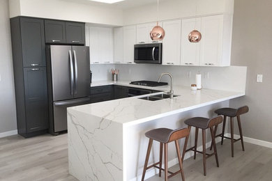 Example of a mid-sized trendy u-shaped light wood floor and beige floor eat-in kitchen design in San Diego with an undermount sink, shaker cabinets, white cabinets, quartzite countertops, white backsplash, stainless steel appliances, a peninsula, white countertops and stone slab backsplash