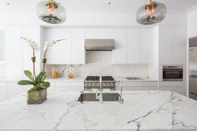 Foto på ett mellanstort funkis kök och matrum, med en undermonterad diskho, släta luckor, vita skåp, marmorbänkskiva, vitt stänkskydd, stänkskydd i sten, rostfria vitvaror, ljust trägolv och en köksö