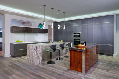 Inspiration for a mid-sized contemporary galley light wood floor and gray floor open concept kitchen remodel in Other with a double-bowl sink, flat-panel cabinets, gray cabinets, marble countertops, white backsplash, stainless steel appliances, two islands and glass sheet backsplash