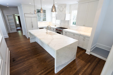 Foto di un cucina con isola centrale chic con lavello sottopiano, ante con riquadro incassato, top in marmo, paraspruzzi bianco, paraspruzzi in marmo, parquet scuro e top bianco