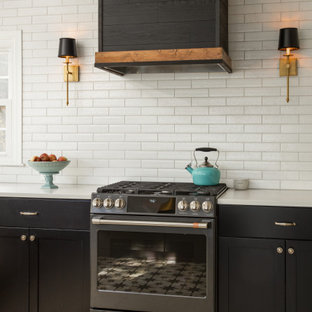 Photo of a large u-shaped open plan kitchen in DC Metro with a drop-in sink, shaker cabinets, black cabinets, quartz benchtops, white splashback, porcelain splashback, black appliances, porcelain floors, a peninsula, multi-coloured floor and white benchtop.