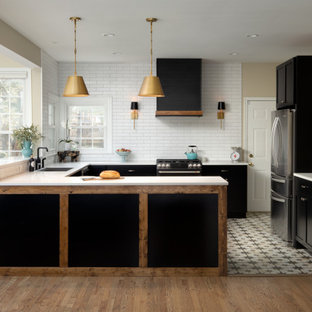 Inspiration for a large country u-shaped open plan kitchen in DC Metro with a drop-in sink, shaker cabinets, black cabinets, quartz benchtops, white splashback, porcelain splashback, black appliances, porcelain floors, a peninsula, multi-coloured floor and white benchtop.