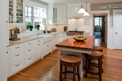 Large farmhouse l-shaped medium tone wood floor and brown floor enclosed kitchen photo in Philadelphia with a farmhouse sink, shaker cabinets, white cabinets, wood countertops, white backsplash, stainless steel appliances, an island and subway tile backsplash