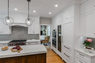 ボストンにある高級な広いトランジショナルスタイルのおしゃれなキッチン (アンダーカウンターシンク、落し込みパネル扉のキャビネット、白いキャビネット、クオーツストーンカウンター、グレーのキッチンパネル、ガラスタイルのキッチンパネル、シルバーの調理設備、淡色無垢フローリング、茶色い床、白いキッチンカウンター) の写真