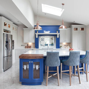 Design ideas for an expansive transitional l-shaped open plan kitchen in Dublin with an integrated sink, louvered cabinets, blue cabinets, quartzite benchtops, white splashback, stone slab splashback, stainless steel appliances, ceramic floors and with island.