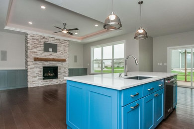 Inspiration for a medium sized classic single-wall open plan kitchen in Chicago with a submerged sink, shaker cabinets, blue cabinets, composite countertops, white splashback, ceramic splashback, stainless steel appliances, dark hardwood flooring, an island and brown floors.