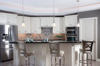 Inspiration for a mid-sized transitional galley medium tone wood floor and gray floor eat-in kitchen remodel in Toronto with an undermount sink, recessed-panel cabinets, white cabinets, granite countertops, multicolored backsplash, glass sheet backsplash, stainless steel appliances and a peninsula