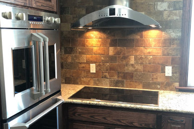 Example of a mid-sized classic u-shaped eat-in kitchen design in Houston with raised-panel cabinets, dark wood cabinets, granite countertops, brown backsplash, an island and multicolored countertops