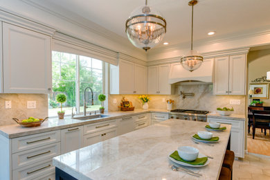 Photo of a classic kitchen in San Francisco with a submerged sink, recessed-panel cabinets, white cabinets, stainless steel appliances, an island, beige floors and beige worktops.