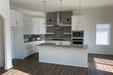 Mid-sized minimalist l-shaped vinyl floor and multicolored floor open concept kitchen photo in Omaha with granite countertops, gray backsplash, ceramic backsplash, stainless steel appliances, multicolored countertops, a farmhouse sink, an island and white cabinets
