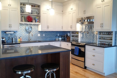 Example of a large classic l-shaped light wood floor eat-in kitchen design in Minneapolis with an undermount sink, recessed-panel cabinets, white cabinets, blue backsplash, subway tile backsplash, stainless steel appliances, an island and granite countertops