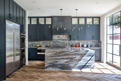 Trendy kitchen photo in Los Angeles with black cabinets, an island and marble backsplash