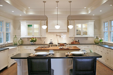 Example of a large classic u-shaped medium tone wood floor eat-in kitchen design in Atlanta with a farmhouse sink, recessed-panel cabinets, white cabinets, white backsplash, stainless steel appliances and two islands