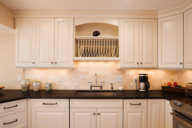 Inredning av ett lantligt kök, med en undermonterad diskho, luckor med upphöjd panel, vita skåp, beige stänkskydd, stänkskydd i stenkakel, rostfria vitvaror, ljust trägolv och en halv köksö