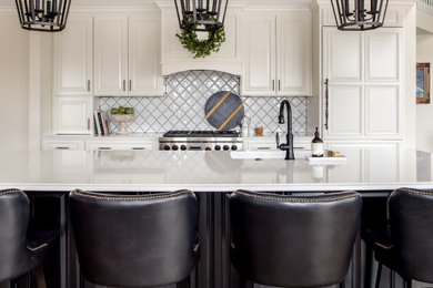 Example of a classic kitchen design in Denver with white cabinets, quartz countertops, white backsplash, ceramic backsplash, paneled appliances, an island and white countertops