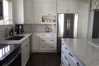 Inspiration for a mid-sized transitional l-shaped vinyl floor kitchen remodel in Toronto with an undermount sink, recessed-panel cabinets, white cabinets, quartz countertops, stone tile backsplash, stainless steel appliances and an island