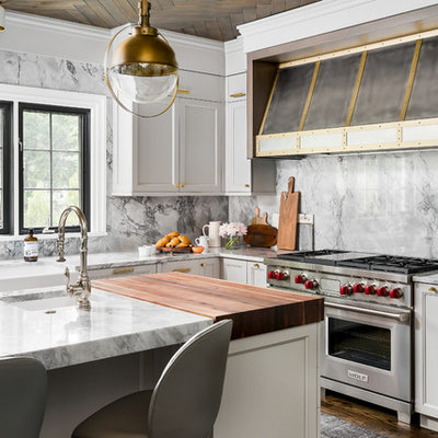 Mid-sized transitional l-shaped medium tone wood floor and brown floor enclosed kitchen photo in Chicago with a farmhouse sink, recessed-panel cabinets, gray cabinets, quartzite countertops, gray backsplash, stone slab backsplash, an island, gray countertops and stainless steel appliances