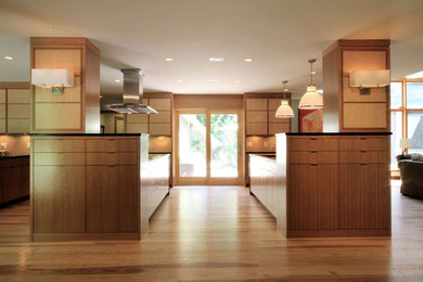 Foto på ett funkis kök med öppen planlösning, med en undermonterad diskho, släta luckor, skåp i mellenmörkt trä, granitbänkskiva och rostfria vitvaror