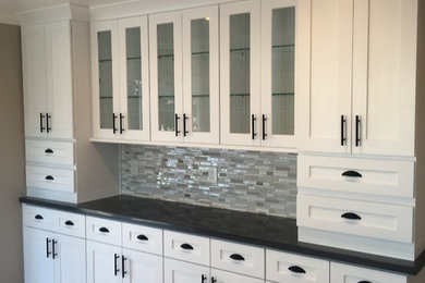 Example of a mid-sized classic light wood floor kitchen design in San Francisco with shaker cabinets, white cabinets, solid surface countertops, multicolored backsplash and matchstick tile backsplash