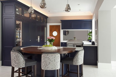 Inspiration for a large traditional u-shaped kitchen/diner in Dublin with a belfast sink, beaded cabinets, blue cabinets, quartz worktops, metallic splashback, mirror splashback, stainless steel appliances, ceramic flooring, an island, blue floors and white worktops.