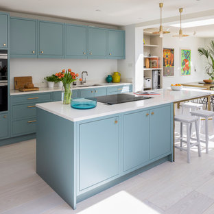 Medium sized contemporary galley open plan kitchen in London with a double-bowl sink, flat-panel cabinets, blue cabinets, quartz worktops, stainless steel appliances, light hardwood flooring, an island, white floors, white worktops and white splashback.