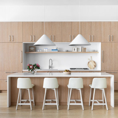 Large trendy u-shaped light wood floor and brown floor eat-in kitchen photo in New York with a drop-in sink, flat-panel cabinets, light wood cabinets, wood countertops, white backsplash, marble backsplash, stainless steel appliances, an island and white countertops