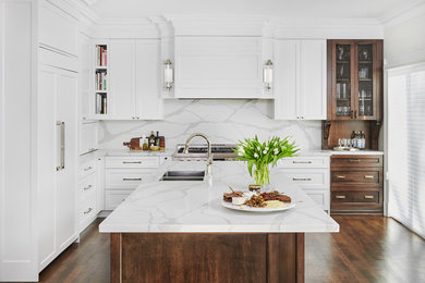 Inspiration for a large transitional l-shaped dark wood floor and brown floor open concept kitchen remodel in Toronto with an undermount sink, shaker cabinets, solid surface countertops, white backsplash, stone slab backsplash, paneled appliances, an island, white countertops and white cabinets