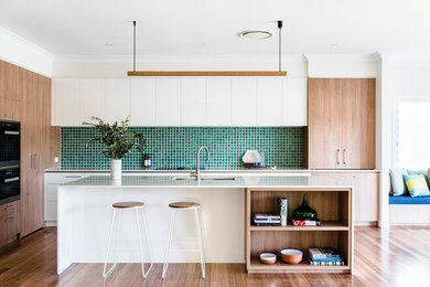 Design ideas for a contemporary l-shaped kitchen in Brisbane with a submerged sink, flat-panel cabinets, white cabinets, green splashback, stainless steel appliances, medium hardwood flooring, an island, brown floors and white worktops.