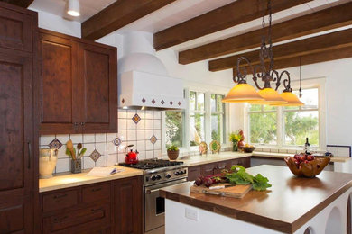 Large u-shaped kitchen in San Diego with dark wood cabinets, wood worktops, white splashback and an island.
