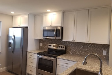 Example of a mid-sized transitional l-shaped vinyl floor eat-in kitchen design in Other with an undermount sink, shaker cabinets, white cabinets, quartz countertops, glass sheet backsplash and gray countertops