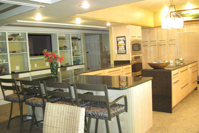 This is an example of a large contemporary u-shaped kitchen/diner in Miami with a submerged sink, flat-panel cabinets, light wood cabinets, granite worktops, integrated appliances, concrete flooring and an island.