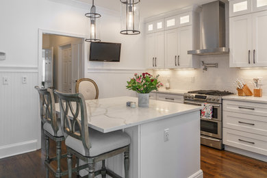 Example of a mid-sized farmhouse u-shaped dark wood floor and brown floor kitchen pantry design in Atlanta with a farmhouse sink, shaker cabinets, white cabinets, solid surface countertops, white backsplash, subway tile backsplash, stainless steel appliances, an island and white countertops