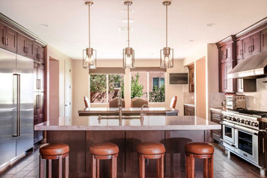 Example of a large arts and crafts galley medium tone wood floor and brown floor eat-in kitchen design in Las Vegas with an undermount sink, shaker cabinets, dark wood cabinets, marble countertops, gray backsplash, marble backsplash, stainless steel appliances, two islands and gray countertops