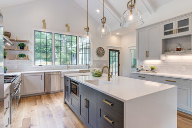 Kitchen - large country u-shaped light wood floor kitchen idea in Raleigh with a farmhouse sink, shaker cabinets, gray cabinets, gray backsplash, stainless steel appliances, an island and white countertops