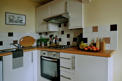 Photo of a small contemporary u-shaped open plan kitchen in Other with a single-bowl sink, flat-panel cabinets, white cabinets, laminate countertops, multi-coloured splashback, ceramic splashback, stainless steel appliances and no island.