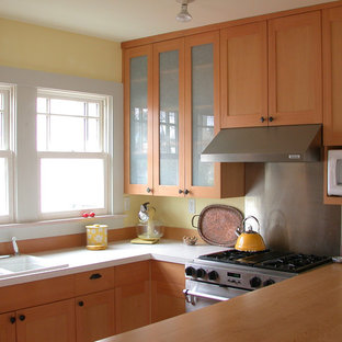 Inspiration for a mid-sized arts and crafts galley open plan kitchen in Seattle with a double-bowl sink, shaker cabinets, light wood cabinets, quartzite benchtops, yellow splashback, white appliances, light hardwood floors and a peninsula.